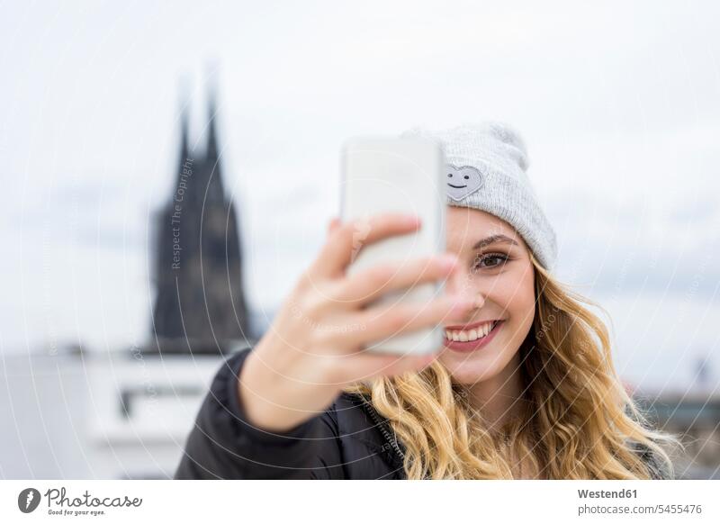 Germany, Cologne, portrait of laughing young woman taking selfie with smartphone Smartphone iPhone Smartphones portraits Selfie Selfies females women Laughter