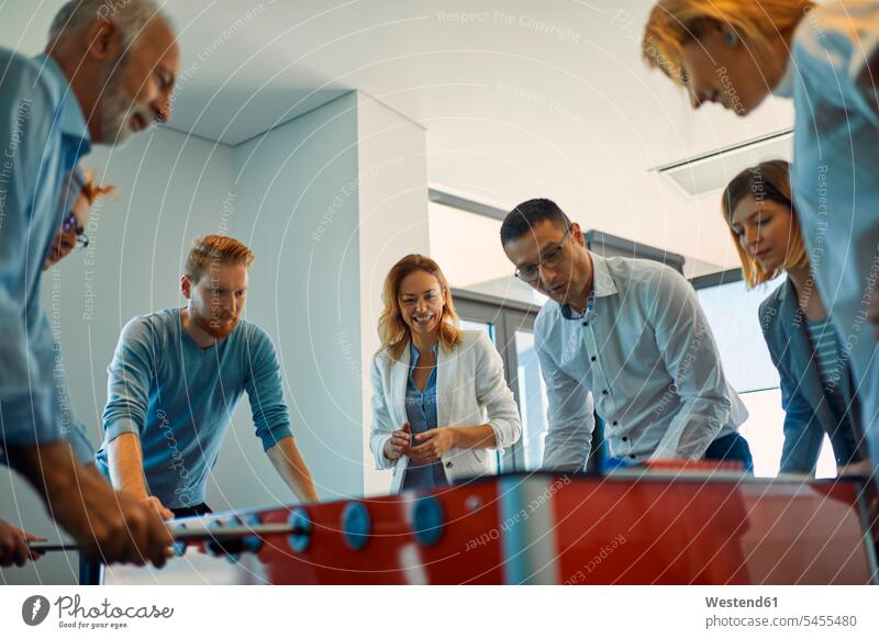 Colleagues playing foosball in office colleagues offices office room office rooms table football table soccer workplace work place place of work Taking a Break