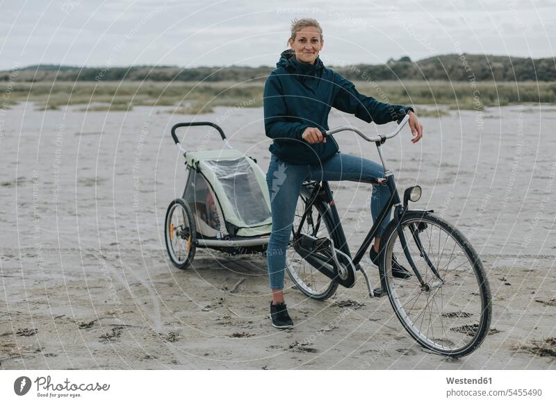 Netherlands, Schiermonnikoog, woman with bicycle and trailer on the beach bikes bicycles females women beaches Adults grown-ups grownups adult people persons