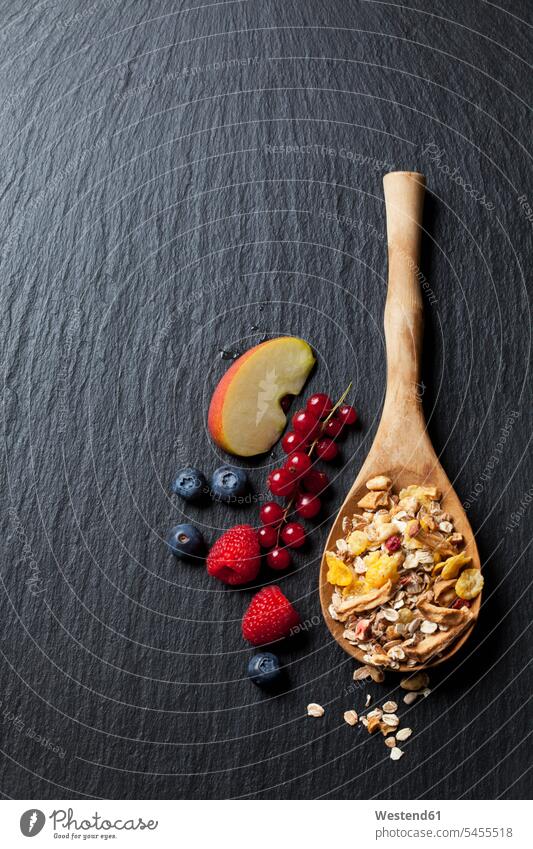 Wooden spoon of granola with dried fruits and various fresh fruits on slate black background black backgrounds blackberry blackberries blackberry fruit Apple