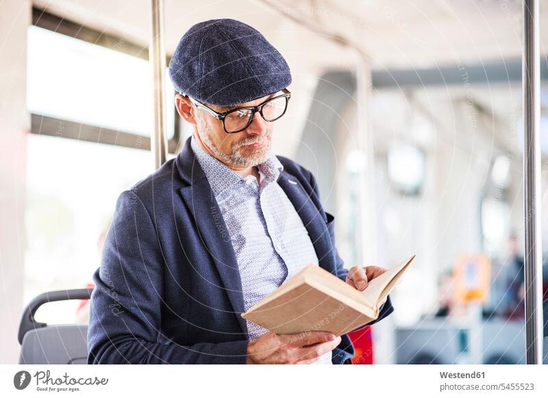 Man in bus reading book commuter commuters man men males busses books Adults grown-ups grownups adult people persons human being humans human beings