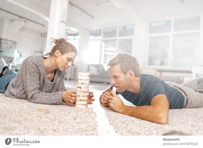 Couple lying on the floor playing jenga laying down lie lying down floors couple twosomes partnership couples people persons human being humans human beings