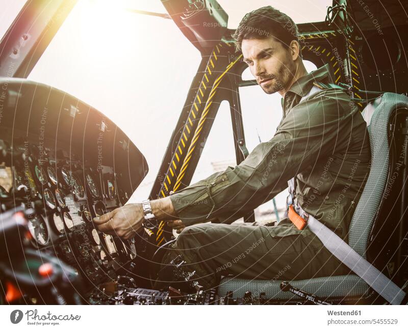 Pilot in cockpit of a helicopter pilot pilots aircraft Air Vehicle aircrafts Air Vehicles transportation man men males adjusting setting cool attitude composed