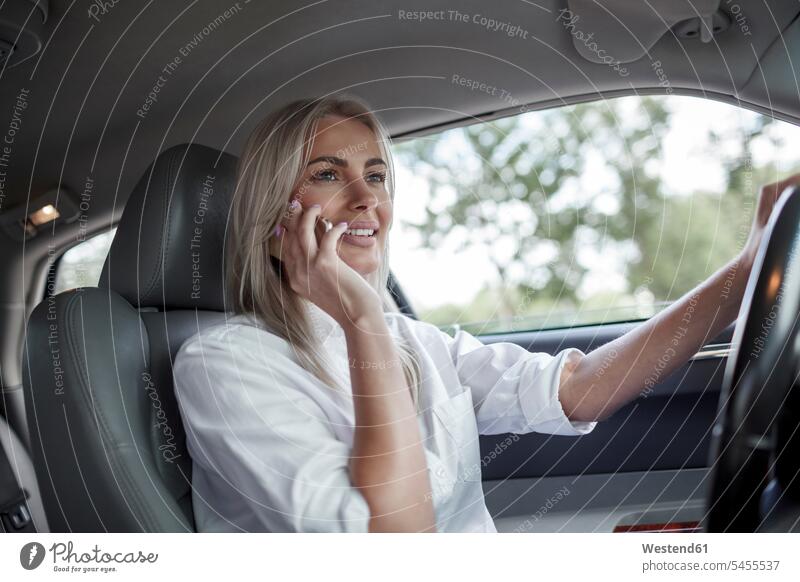 Smiling businesswoman on cell phone driving car drive smiling smile on the phone call telephoning On The Telephone calling mobile phone mobiles mobile phones