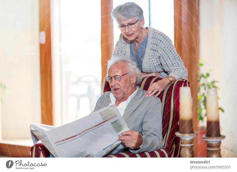 Senior man and woman sitting in library, reading newspaper senior men senior man elder man elder men senior citizen retirement home nursing home senior women