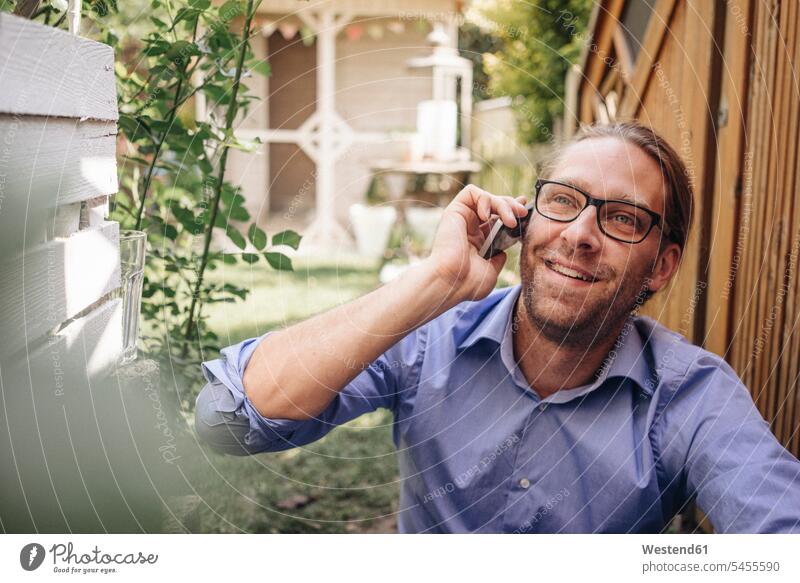 Man on the phone in garden gardens domestic garden man men males call telephoning On The Telephone calling smiling smile relaxed relaxation mobile phone mobiles