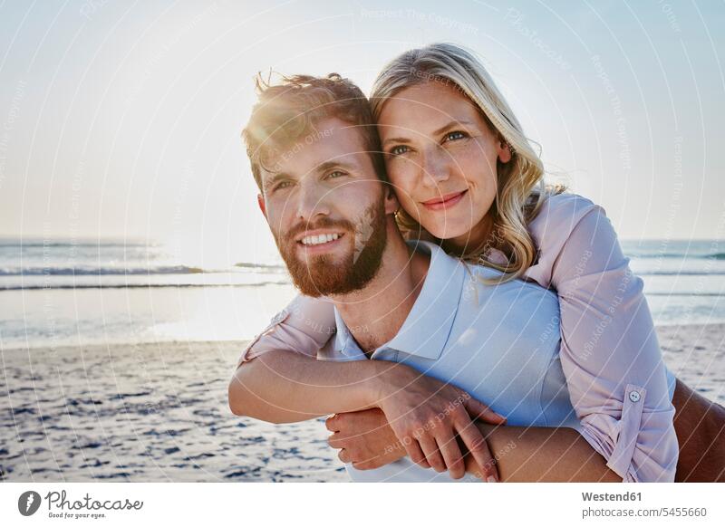 Portrait of happy couple on the beach happiness piggyback piggy-back pickaback Piggybacking Piggy Back smiling smile beaches twosomes partnership couples people