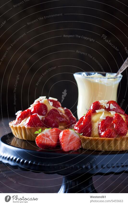 Two strawberry tartlets with custard and white chocolate shaving on cake stand Glass Glasses garnished sliced ready to eat ready-to-eat short crust short pastry