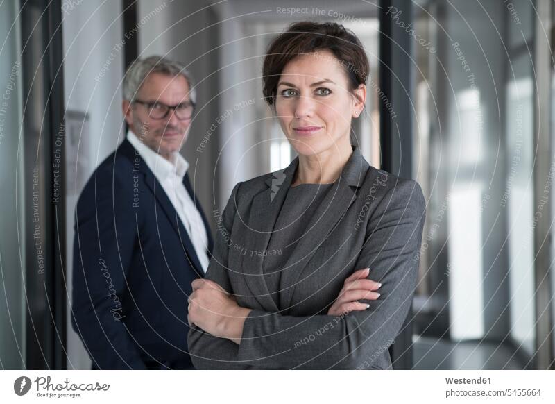Portrait of confident businesswoman with businessman in background businesswomen business woman business women portrait portraits business people businesspeople