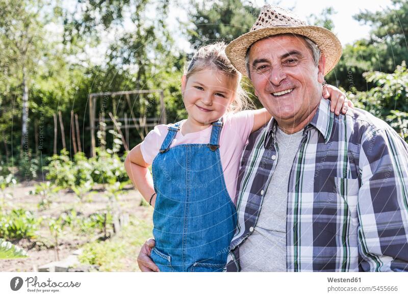 Portrait of smiling grandfather and granddaughter in the garden grandpas granddads grandfathers smile gardens domestic garden granddaughters grandparents family