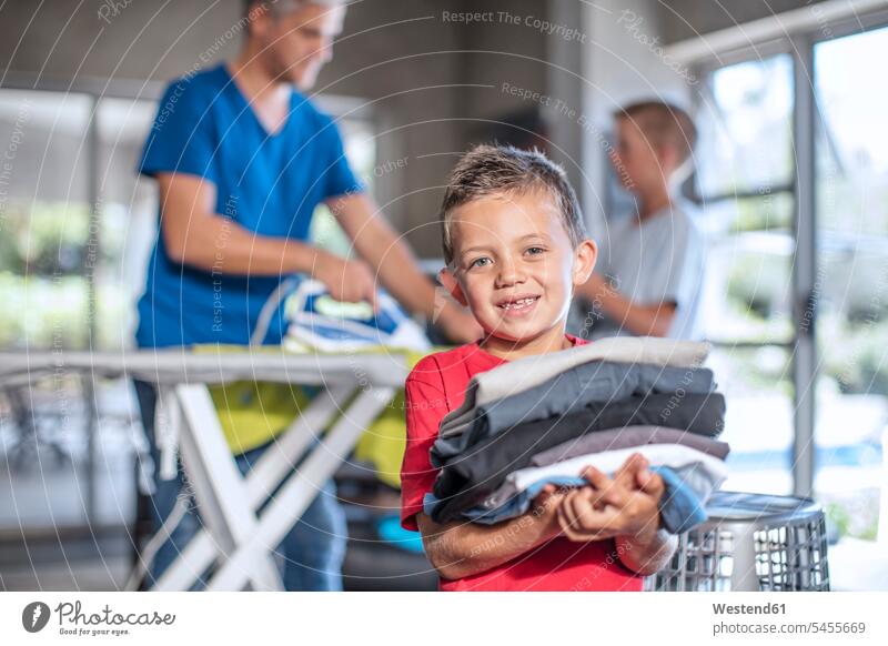 Smiling boy helping with chores holding folded clothes carrying smiling smile assistance assisting Help home at home Laundry boys males father pa fathers daddy