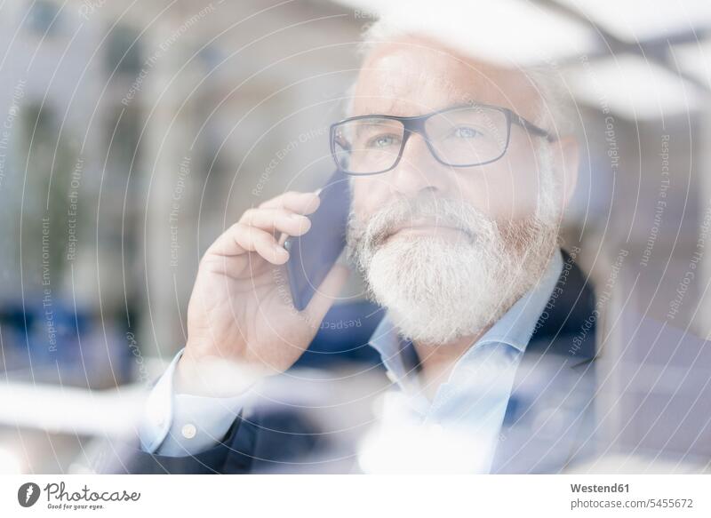 Mature man on cell phone behind windowpane windows Businessman Business man Businessmen Business men males on the phone call telephoning On The Telephone