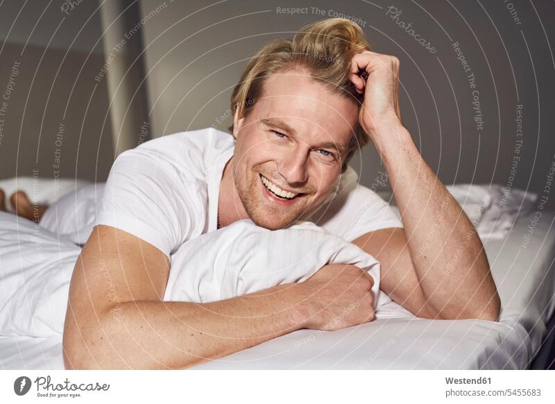 Portrait of laughing young man lying on bed portrait portraits beds men males Adults grown-ups grownups adult people persons human being humans human beings