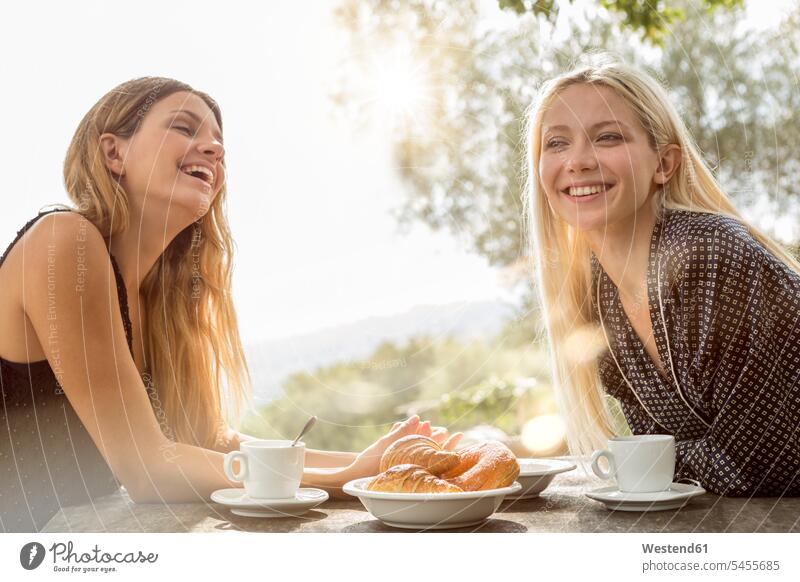 Two laughing friends at breakfast table in the morning female friends mate friendship drinking portrait portraits woman females women Laughter Breakfast