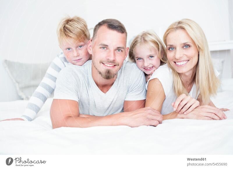 Portrait of smiling family lying in bed laying down lie lying down relaxed relaxation portrait portraits beds families smile relaxing people persons human being
