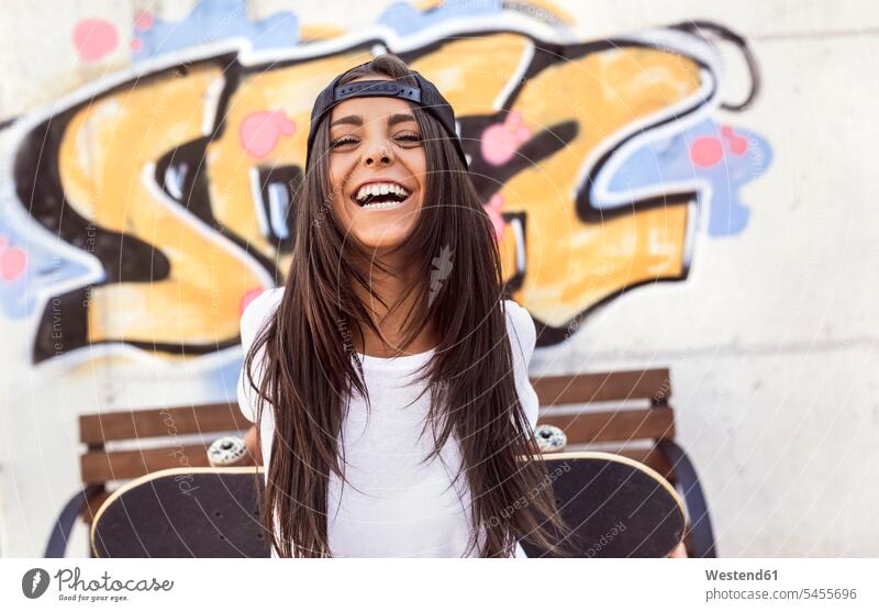 Laughing young woman holding skateboard laughing Laughter females women Skate Board skateboards positive Emotion Feeling Feelings Sentiments Emotions emotional