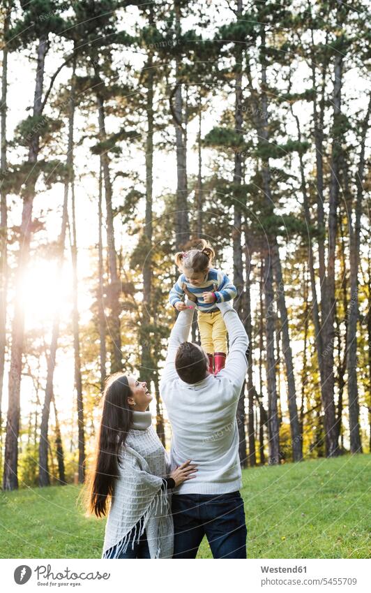 Playful parents with girl in forest happiness happy family families females girls Fun having fun funny people persons human being humans human beings child