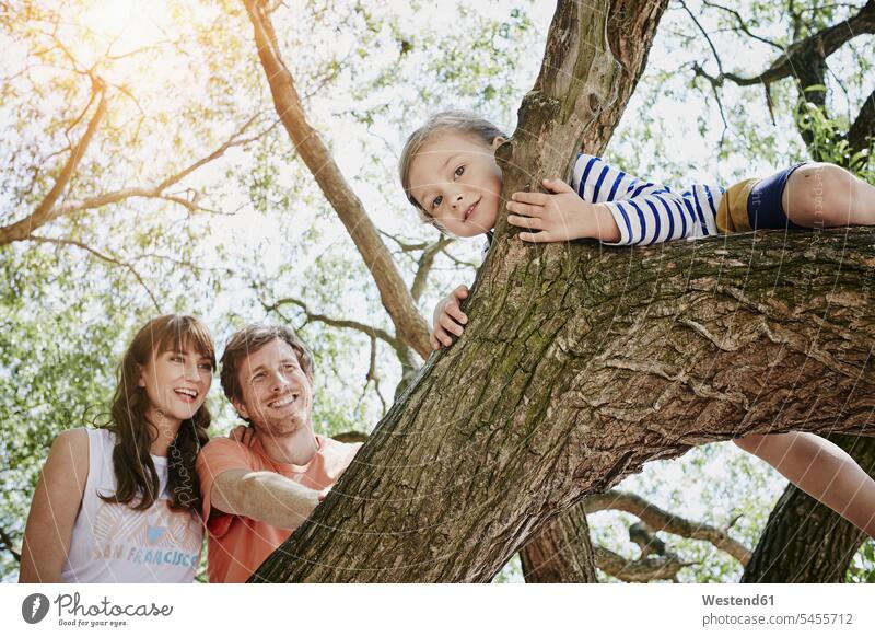 Parents watching daughter climbing on a tree smiling smile Tree Trees family families people persons human being humans human beings looking view seeing viewing