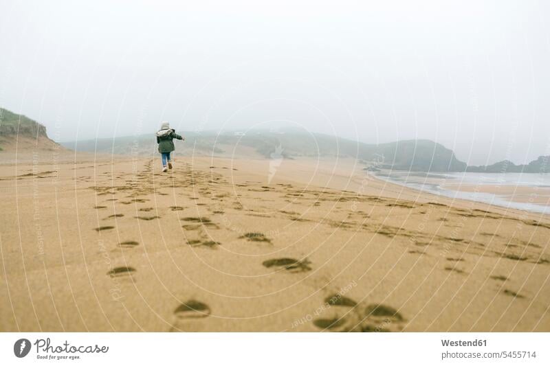 Girl running on the beach on a foggy winter day beaches girl females girls child children kid kids people persons human being humans human beings Sea ocean
