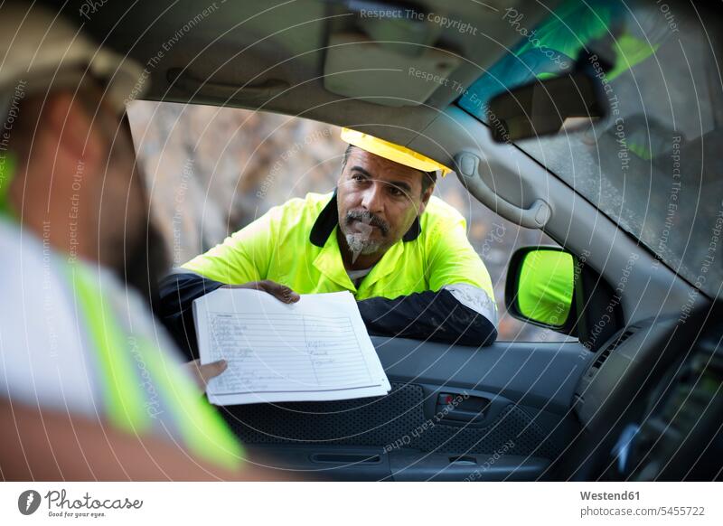 Worker handing over documents to colleague sitting in car protective clothing Protective Wear gravel pit reflective vest reflector-vest reflector vest