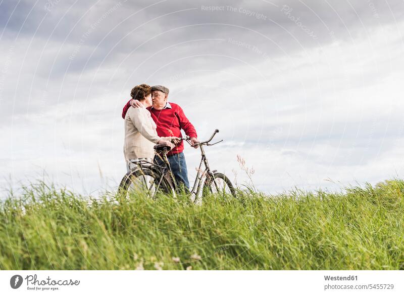 Senior couple with bicycles kissing in rural landscape twosomes partnership couples senior men senior man elder man elder men senior citizen senior women