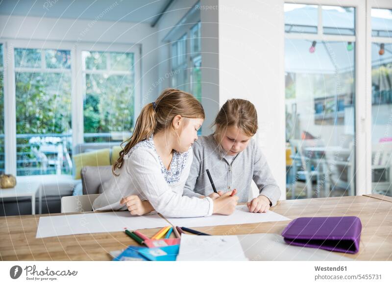 Two girls doing homework at table together female friends Table Tables Home work females mate friendship child children kid kids people persons human being