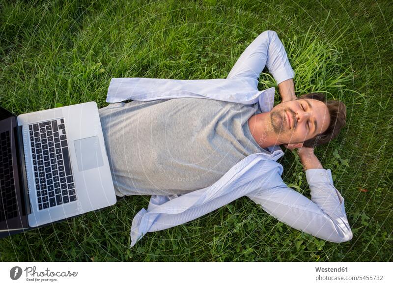 Man relaxing on the grass in summer, with laptop on his belly Laptop Computers laptops notebook man men males daydreaming day dreaming Daydreams Day Dream