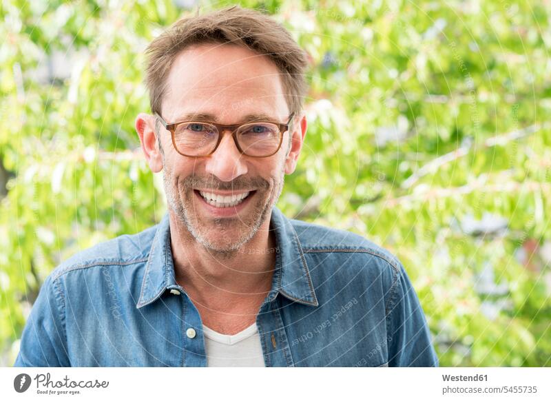 Portrait of laughing mature man with stubble wearing glasses men males portrait portraits Adults grown-ups grownups adult people persons human being humans