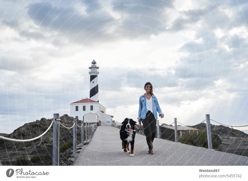Spain, Menorca, Bernese mountain dog walking together with his owner outdoors at lighthouse dogs Canine Bernese mountain dogs Bernese cattle dog