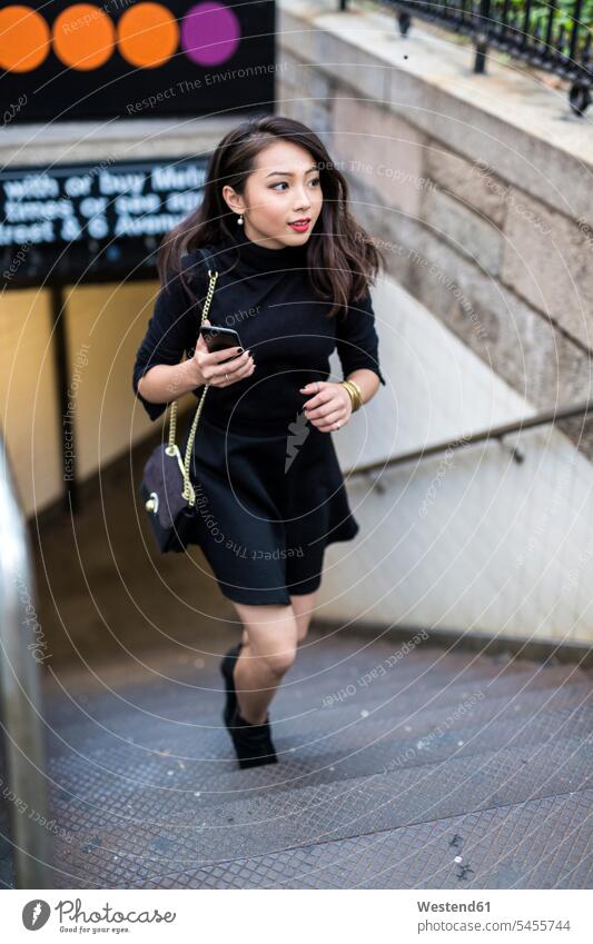USA, New York City, Manhattan, young woman dressed in black walking upstairs females women Adults grown-ups grownups adult people persons human being humans