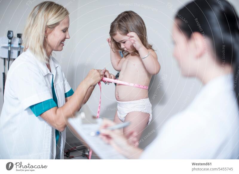 Doctor measuring a little patient tape measure measuring tapes tape measures Measure Tape measurement pediatrician paediatricians girl females girls doctor