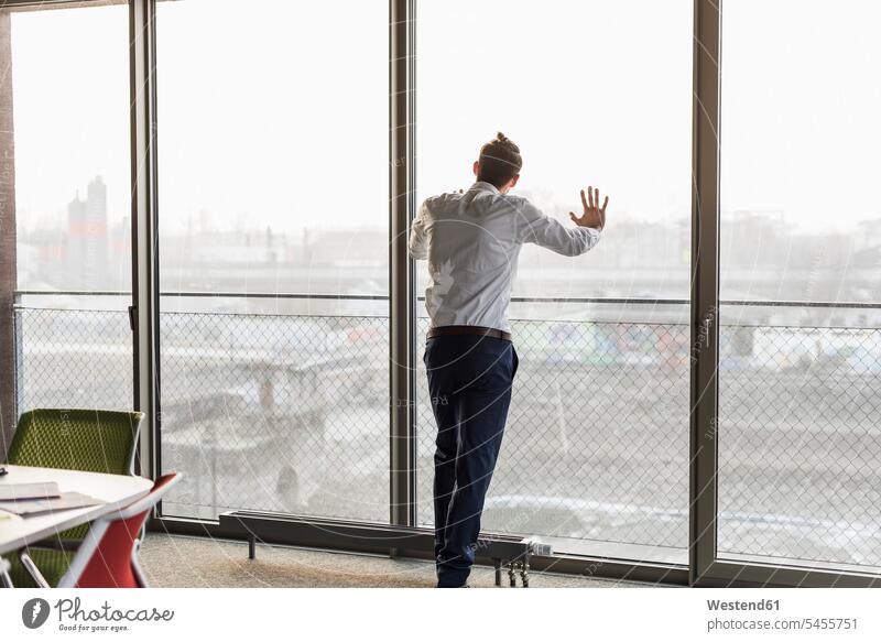 Young businessman looking out of window view seeing viewing Businessman Business man Businessmen Business men windows business people businesspeople
