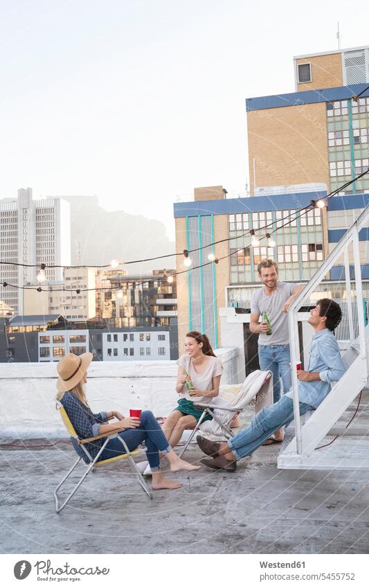 Friends having a rooftop party on a beautiful summer evening enjoying indulgence enjoyment savoring indulging drinking together roof terrace deck summer time