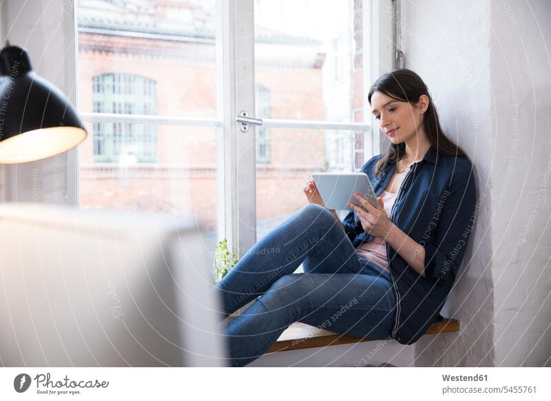Woman using tablet at the window in office offices office room office rooms workplace work place place of work working At Work woman females women digitizer