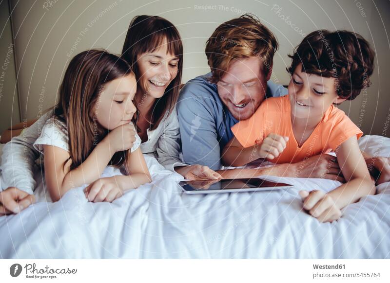 Children and their parents looking at tablet on bed digitizer Tablet Computer Tablet PC Tablet Computers iPad Digital Tablet digital tablets laughing Laughter