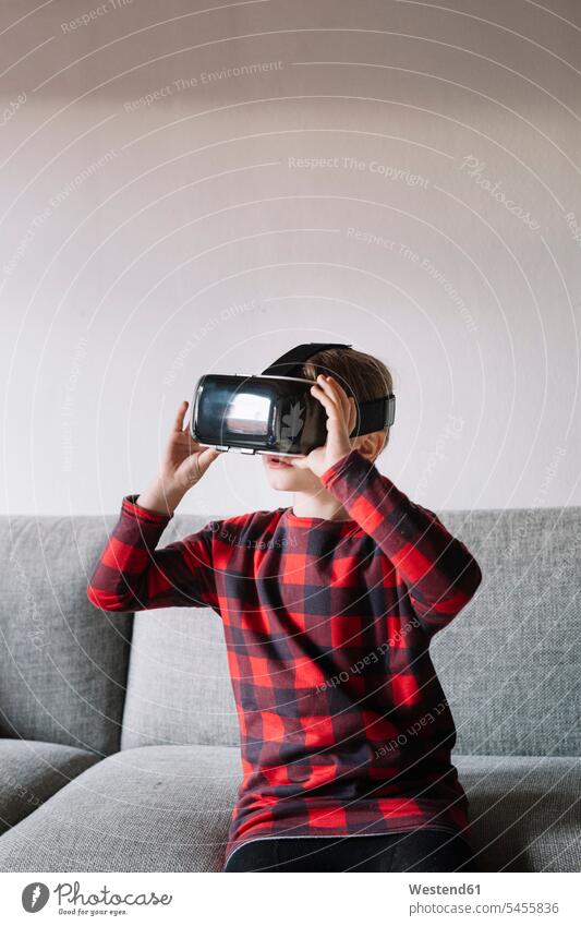 Girl sitting on the couch in the living room using Virtual Reality Glasses settee sofa sofas couches settees use VR glasses Virtual-Reality Glasses
