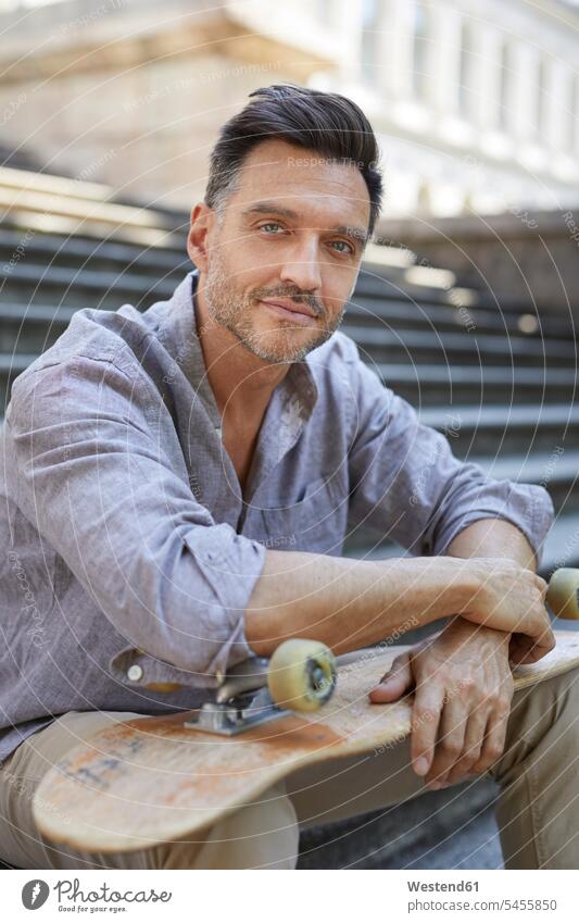 Portrait of relaxed mature man with skateboard sitting on stairs men males Skate Board skateboards portrait portraits Adults grown-ups grownups adult people