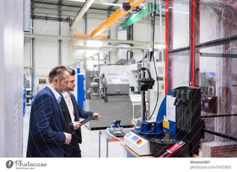 Two businessmen in factory shop floor examining machine colleagues Businessman Business man Businessmen Business men factories business people businesspeople