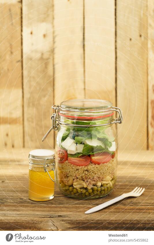 Preserving jar of mixed salad with peas, tuna, couscous, tomatoes, tuna, feta and jar of vinaigrette dressing homemade home made home-made Leaf Salad