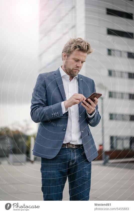 Businessman using cell phone in the city use Business man Businessmen Business men town cities towns mobile phone mobiles mobile phones Cellphone cell phones