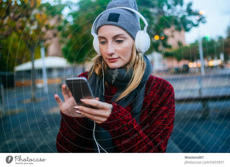 Young woman listening to music with a smartphone hearing headphones headset mobile phone mobiles mobile phones Cellphone cell phone cell phones females women