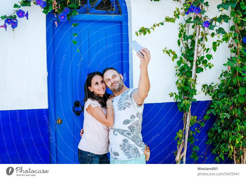 Morocco, Tanger, couple taking selfie with smartphone in front of blue door doors Smartphone iPhone Smartphones Selfie Selfies twosomes partnership couples