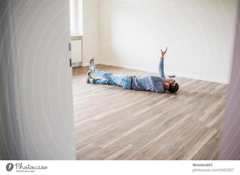 Man lying on the floor in empty apartment wearing VR glasses laying down lie lying down Virtual Reality Glasses Virtual-Reality Glasses virtual reality headset