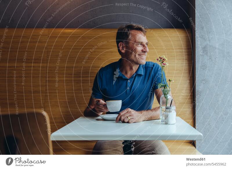 Smiling mature man sitting in cafe Seated smiling smile men males Adults grown-ups grownups adult people persons human being humans human beings casual