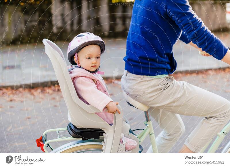 Mother and daughter riding bicycle, baby wearing helmet sitting in children's seat Child's Seat child seat child safety seat cycling helmet Bike Helmet