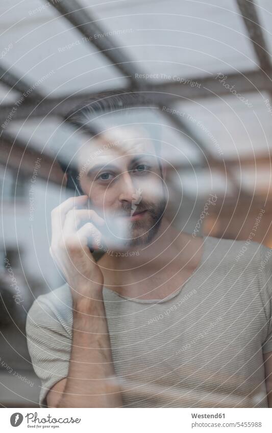 Portrait of young man on the phone behind windowpane men males call telephoning On The Telephone calling Adults grown-ups grownups adult people persons