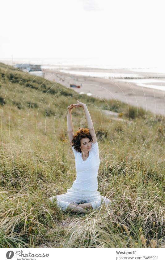 Woman stretching in beach dune sand dune sand dunes yoga woman females women beaches mindfulness aware awareness self-care relaxation exercise relaxed relaxing