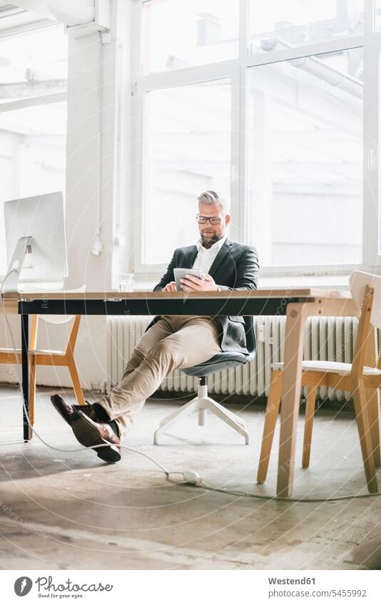 Businessman sitting relaxed in modern office Office Offices Business man Businessmen Business men business people businesspeople business world business life