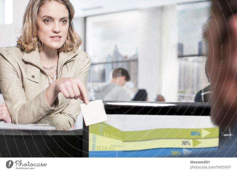 Young woman in office looking at colleague eyeing offices office room office rooms colleagues view seeing viewing workplace work place place of work note notes