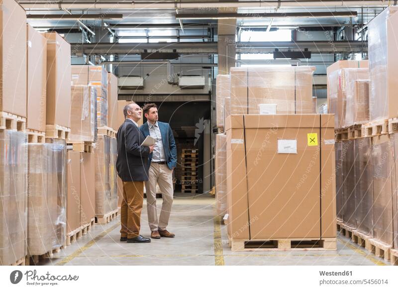 Two men standing in factory warehouse man males working At Work colleagues Businessman Business man Businessmen Business men storehouse storage tablet digitizer